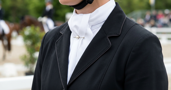 Lavallière blanche épinglée sur veste de concours noire, ambiance dressage