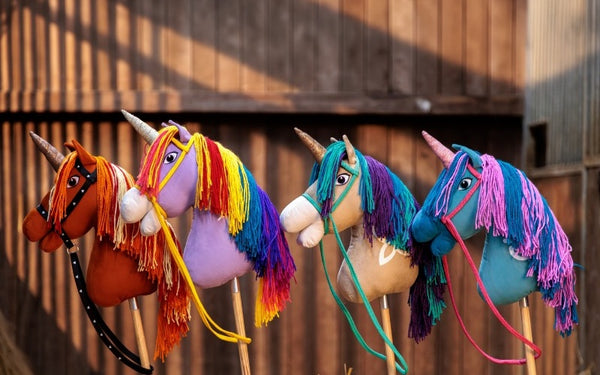 Les quatre chevaux batons Unicorn Academy alignes devant une cloture en bois