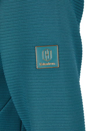 "Patch en cuir bleu avec le logo et le nom de la marque 'Eskadron' sur une surface en tissu texturé bleu canard à rayures horizontales."