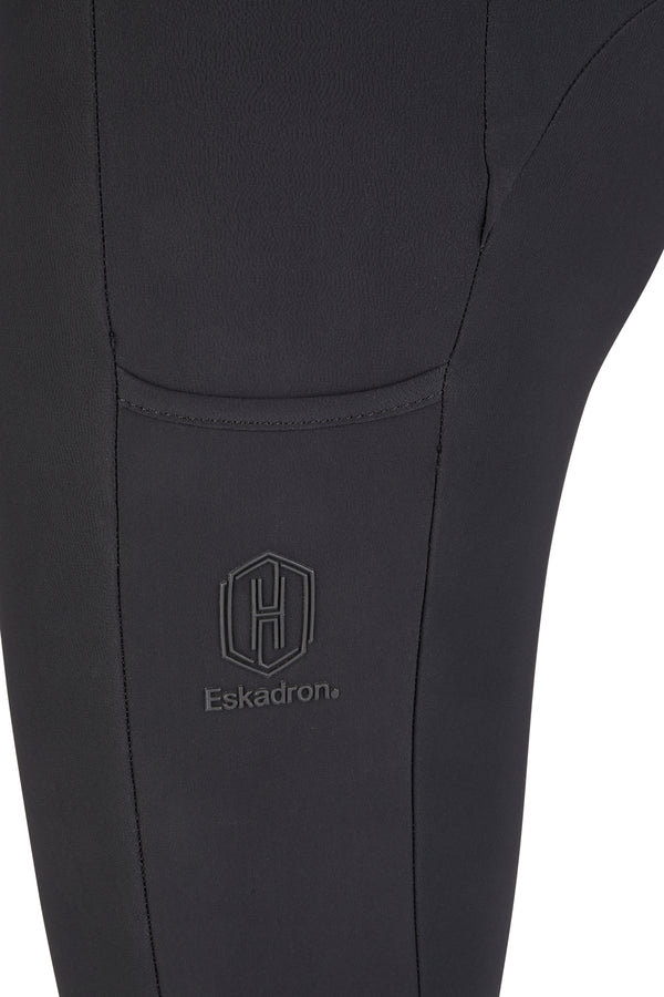 "Vue rapprochée de la jambe d'un pantalon noir de la marque Eskadron, montrant un logo brodé en relief avec les lettres 'E' et 'H' dans un cadre hexagonal."