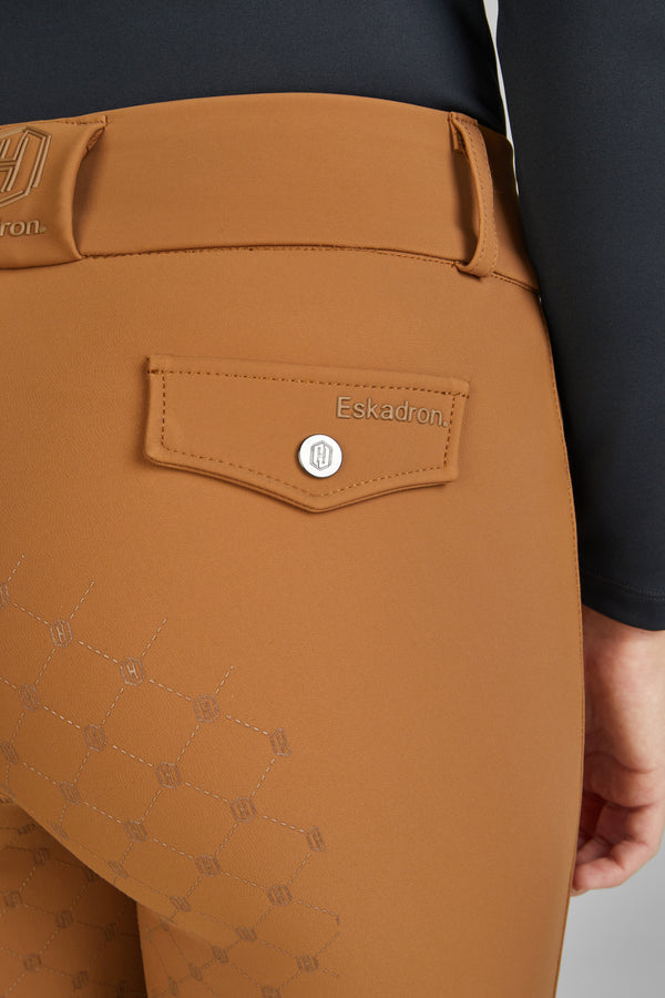 "Vue rapprochée de la partie arrière d'un pantalon d'équitation brun clair de la marque Eskadron, avec un motif géométrique graphique sur le tissu. Une poche avec un bouton argenté et le logo Eskadron est visible. La ceinture du pantalon, également estampillée du logo, est partiellement visible."