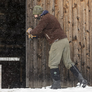 Homme réparant une clôture dans la neige, chaussé de bottes Muck Boot Arctic Sport High
