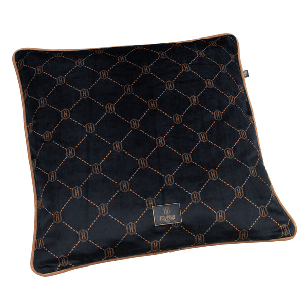 Coussin carré en tissu velouté noir avec un motif de grille géométrique en losanges délimités par des lignes pointillées marron. Chaque intersection du motif est marquée par un logo circulaire avec la lettre "H". Une étiquette noire avec le logo "Eskadron" est cousue sur le devant, dans un coin du coussin. Les bords du coussin sont soulignés par une bordure marron.