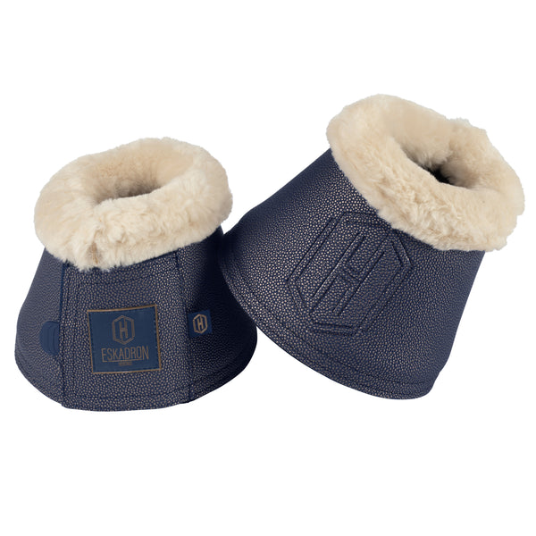 Deux cloches de protection pour chevaux de la marque Eskadron, en cuir synthétique bleu marine avec une doublure en fausse fourrure beige. Ces cloches sont rembourrées pour offrir confort et protection, avec un logo en relief et une étiquette Eskadron visible sur un des côtés.