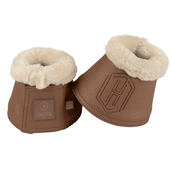 Deux cloches de protection pour chevaux de couleur marron avec une doublure intérieure en fourrure beige. Le produit porte le logo de la marque "Eskadron" sur une étiquette en cuir et un grand motif en relief sur le côté.