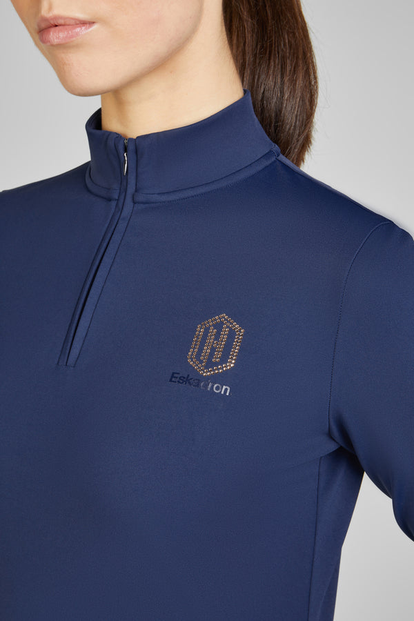 Femme portant un pull bleu marine à col zippé avec un logo doré "Eskadron" sur la poitrine.