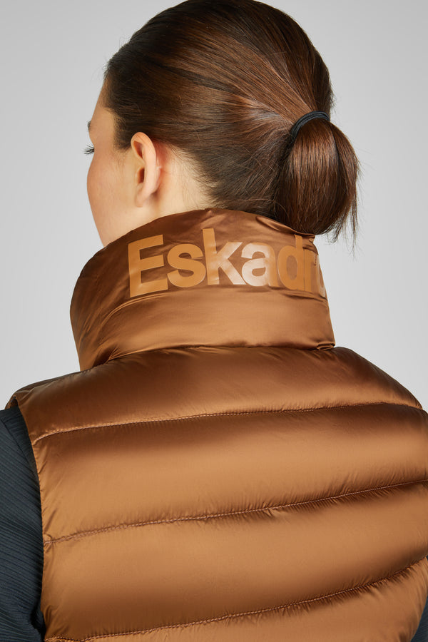 Personne de dos portant une doudoune brune avec un col montant sur lequel est inscrit "Eskadron". Les cheveux sont attachés en un chignon bas.