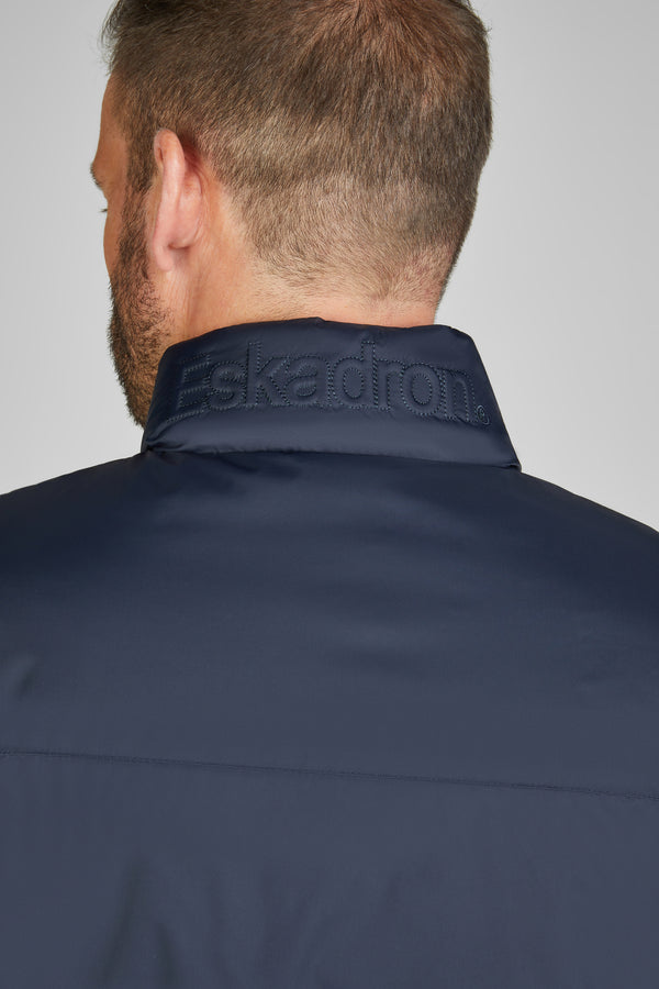 "Vue arrière d'un homme portant une veste bleu foncé avec un col relevé affichant le logo brodé 'Eskadron'."