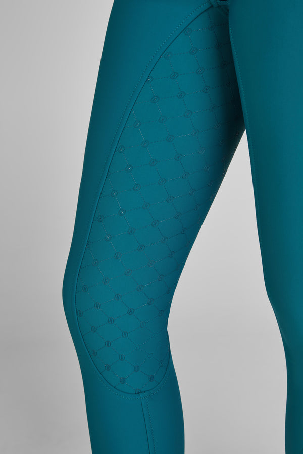 "Vue rapprochée de la jambe d'un pantalon ajusté de couleur bleu canard, avec une surface texturée en motifs hexagonaux sur le côté interne de la cuisse."