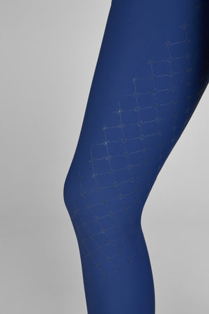 "Vue rapprochée d'une jambe portant un legging bleu avec un motif géométrique discret en forme de losanges sur la partie supérieure."