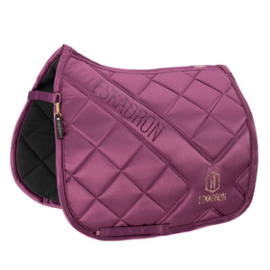 L'image montre une selle d'équitation de couleur violet foncé, visiblement conçue pour l'équitation. Elle est dotée d'un design matelassé, avec des motifs en losange cousus sur toute la surface, offrant à la fois esthétique et confort. Deux éléments de marque sont visibles sur la selle : 1. Le mot "ESKADRON" est inscrit en majuscules le long du côté gauche de la selle, dans une police discrète et élégante. 2. Un logo, composé de deux lettres stylisées "E" et "S", est brodé en bas à droite de...