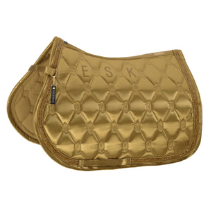L'image montre une selle d'équitation de couleur dorée, conçue avec un motif de losanges en relief. La selle est fabriquée dans un matériau brillant, probablement du satin, qui lui donne un aspect élégant et luxueux. Le bord de la selle est orné d'une bordure brodée avec un fil doré, ajoutant une touche de sophistication supplémentaire. La selle présente trois grandes lettres brodées au centre : "E. S. K.", probablement des initiales. Ces lettres sont également cousues avec du fil doré,...