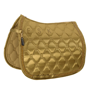 L'image montre une selle d'équitation de couleur dorée avec un design élégant et raffiné. La selle est dotée d'un motif en losanges matelassé, ce qui ajoute une texture et un aspect visuellement attrayant. Les losanges sont disposés de manière régulière, créant un effet de relief sur toute la surface de la selle. Au niveau de l'arrière de la selle, les lettres "E S K" sont brodées en majuscules dorées, offrant une touche personnalisée et sophistiquée. Ces lettres sont placées dans un espace...