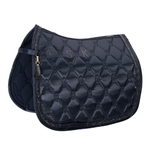 L'image représente une selle d'équitation de haute qualité, conçue avec une attention particulière aux détails et au style. Voici une description détaillée : 1. **Matériau et Design** : - La selle est fabriquée dans un matériau qui semble être du cuir synthétique ou un tissu résistant, offrant une apparence élégante et sophistiquée. - Le design présente un motif géométrique en relief, avec des losanges et des formes hexagonales, ajoutant une texture et un intérêt visuel. 2....