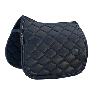 L'image présente une selle de cheval de haute qualité, de couleur bleu foncé, affichant un design élégant et sophistiqué. La selle est ornée de détails méticuleux, mettant en valeur un motif de losanges quiltés qui lui confère texture et profondeur. Voici une description détaillée : 1. **Design quilted** : La surface de la selle est composée de losanges quiltés, créant un motif géométrique répétitif et harmonieux. Chaque losange est soigneusement cousu, offrant un aspect esthétique plaisant...