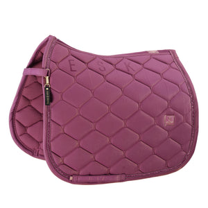 L'image présente une selle d'équitation de couleur mauve. La selle est conçue avec une forme ergonomique pour s'adapter confortablement au dos du cheval. La surface de la selle est matelassée avec un motif en losanges, offrant à la fois style et fonctionnalité. Les losanges sont disposés de manière régulière, créant un aspect texturé et esthétique. Sur le côté droit de la selle, on peut voir les lettres "ESK" brodées en grand, probablement pour identifier le propriétaire ou le cheval. Le...