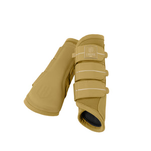 L'image montre une paire de protège-boulets pour chevaux, probablement conçus pour protéger les jambes des chevaux pendant l'entraînement ou les compétitions. Les protège-boulets sont de couleur beige clair avec des éléments de design marron plus foncé. Les protège-boulets sont constitués de plusieurs parties : 1. **Extérieur** : La partie extérieure semble être faite d'un matériau synthétique, peut-être du cuir synthétique ou du plastique, qui offre une protection contre les chocs et les...