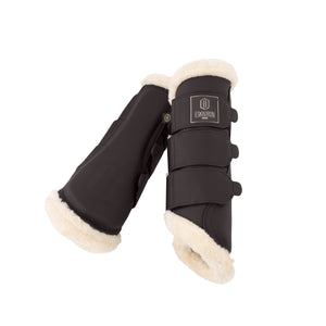 L'image montre une paire de guêtres pour chevaux. Ces guêtres sont conçues pour protéger les jambes des chevaux lors de l'entraînement ou des compétitions. Voici une description détaillée : 1. **Matériau et couleur** : Les guêtres sont principalement fabriquées dans un matériau qui semble être du cuir synthétique, de couleur noire. 2. **Finition** : Les extrémités supérieure et inférieure des guêtres sont bordées d'une fourrure blanche, probablement pour offrir un confort supplémentaire et...