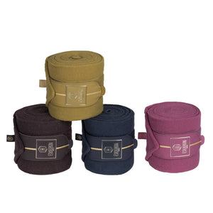 L'image présente un ensemble de quatre bandes de polaire pour chevaux, soigneusement disposées en forme de pyramide. Chaque bande est enroulée et maintenue par une sangle en cuir avec une boucle, offrant un aspect à la fois fonctionnel et esthétique. Les bandes sont de différentes couleurs, ajoutant une touche de variété à la composition. En partant du sommet de la pyramide et en descendant, les couleurs des bandes sont les suivantes : 1. La bande supérieure est de couleur moutarde, une...