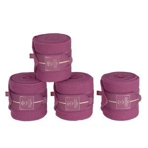 L'image montre un ensemble de quatre bandages pour chevaux, spécifiquement destinés aux membres inférieurs des chevaux. Ces bandages sont de couleur violette unie et sont fabriqués dans un matériau qui semble être une sorte de feutre ou de tissu doux, idéal pour fournir douceur et protection aux jambes d'un cheval. Chaque bandage est roulé et maintenu en place par une sangle, qui arbore une étiquette avec un logo distinct comprenant un mélange de motifs géométriques (notamment un hexagone)...