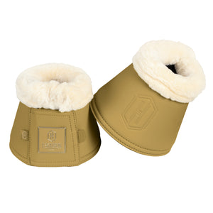 L'image présente une paire de guêtres d'équitation de couleur olive clair, ornées de détails luxueux. Chaque guêtre est composée de deux parties principales : une section inférieure en cuir et une bordure supérieure en fourrure blanche. - **Section inférieure en cuir** : Cette partie de la guêtre est faite d'un cuir olive clair de haute qualité. Sur le côté de chaque guêtre, il y a un emblème en relief représentant un grand "H" stylisé à l'intérieur d'un hexagone. En dessous de cet emblème,...