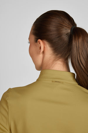 L'image montre une femme vue de dos. Elle a les cheveux longs et bruns attachés en une queue de cheval haute avec un élastique de couleur foncée. La femme porte une veste ou une chemise de couleur olive. La veste est cintrée et semble être faite d'un tissu léger et peut-être imperméable. Sur le col de la veste, il y a une petite étiquette métallique dorée avec le mot "Education" inscrit dessus. L'arrière-plan est simple et de couleur claire, ce qui permet de bien mettre en valeur la veste et...