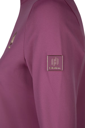 L'image montre un vêtement de couleur violet foncé, probablement un pull ou une veste, vu de très près. Le tissu semble être en matière synthétique, légèrement texturée. Sur la manche, deux éléments distinctifs sont visibles : 1. Un logo ou emblème rectangulaire avec un design élégant et stylisé. Il présente des lignes délicates et des détails en relief qui forment un motif géométrique. Sous ce design, le mot "Essexion" est inscrit en petites lettres. 2. Un autre logo ou emblème, positionné...