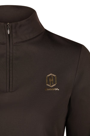 L'image montre un haut à manches longues de couleur marron foncé, conçu avec un style élégant et sportif. Le vêtement présente une fermeture éclair partielle qui remonte jusqu'à un col haut, offrant une protection contre le froid tout en restant stylé. Sur le côté gauche de la poitrine, il y a un logo brodé distinctif. Ce logo se compose d'un losange estampillé avec un « H » stylisé et le mot « Eskadron » inscrit en dessous. Le tissu semble être en matière technique, probablement pour offrir...