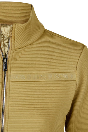 L'image représente un gros plan d'une veste zippée en tissu matelassé de couleur jaune moutarde. La texture du tissu semble être en relief, avec des lignes horizontales qui donnent un aspect légèrement structuré à la veste. Le col de la veste est haut et ajusté, offrant une bonne protection contre le froid. Le zip, de couleur argentée, est de haute qualité et est complètement fermé sur l'image. Il est équipé d'une tirette métallique pour faciliter l'ouverture et la fermeture. Deux...