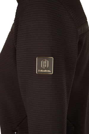 L'image représente un gros plan d'un vêtement noir, plus précisément une veste ou un pull. Le tissu semble avoir une texture tricotée avec des motifs en relief, ce qui lui donne un aspect texturé et sophistiqué. Au centre de l'image, il y a un logo rectangulaire doré et noir cousu sur le vêtement. Le logo est composé d'une bordure dorée entourant un fond noir. À l'intérieur de ce cadre, on peut voir un motif stylisé de trois lettres "H" disposées verticalement, avec des lignes horizontales...