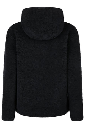 L'image montre un vêtement vu de dos, plus précisément une veste ou un sweat-shirt à capuche de couleur noire. La texture de ce vêtement est pelucheuse et douce, rappelant la texture d'une matière type teddy ou fourrure synthétique. La capuche, bien visible, semble spacieuse et est également en tissu noir et pelucheux. Les manches longues du vêtement sont bien ajustées et se terminent par des poignets non visibles sur cette vue. Le dos de la veste est dépourvu de tout détail, logo ou dessin,...