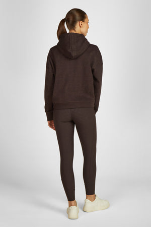 L'image représente une femme vue de dos, portant une tenue décontractée et sportive. Elle est vêtue d'un sweat-shirt à capuche marron foncé avec des motifs scintillants ou pailletés, offrant un style à la fois casual et élégant. Le sweat-shirt dispose d'une capuche et de manches longues. La femme porte également un legging marron assorti qui s'étend jusqu'aux chevilles, ajusté mais confortable, adapté pour des activités sportives ou pour un look décontracté. Elle complète sa tenue avec une...