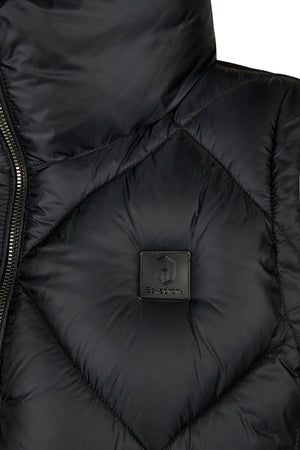 L'image montre un gros plan d'une veste en matière synthétique, probablement imperméable et isolante, de couleur noire. La veste présente une texture matelassée avec des coutures en losanges, typique des vestes rembourrées pour offrir une bonne isolation thermique. Au centre de l'image, on peut voir un patch carré en cuir ou en similicuir, également de couleur noire. Ce patch est cousu sur la veste et affiche un logo distinctif. Le logo se compose d'un "H" stylisé, placé au centre d'un...