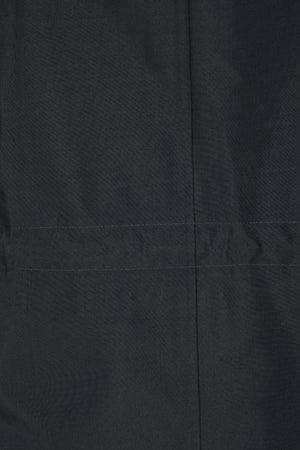 Cette image montre une vue rapprochée d'un vêtement noir, probablement une veste ou un blouson. Le tissu semble être de haute qualité, avec une texture fine et régulière. La caractéristique principale visible est une étiquette ou un logo situé horizontalement, légèrement au-dessus du centre. Ce logo est en relief, avec des lettres en blanc qui forment le mot "BOSS". Le contraste entre le noir du tissu et le blanc des lettres rend le logo très visible et distinct. La couture est discrète...