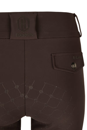 L'image présente une vue rapprochée de la partie postérieure d'un pantalon d'équitation de la marque Eskadron. Le pantalon est de couleur marron foncé et présente plusieurs caractéristiques distinctives. 1. **Logo et Marque** : - Le logo de la marque Eskadron est bien visible sur le pantalon. Il est présent sous deux formes : - Un logo plus grand en haut de la ceinture du pantalon. Le logo est une forme hexagonale avec la lettre "H" en son centre. - Un autre logo plus petit est...