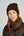 Sur cette image, on voit une personne portant un bonnet noir en tissu moelleux et un manteau noir. Le bonnet est épais et douillet, adapté pour les périodes froides. Il présente un logo ou une étiquette carrée sur le devant, légèrement sur le côté. La personne a des cheveux longs et bruns qui tombent librement sur ses épaules. Son expression est neutre et elle regarde directement l'objectif de la caméra. Le manteau qu'elle porte semble être une veste matelassée, conçue pour offrir une...