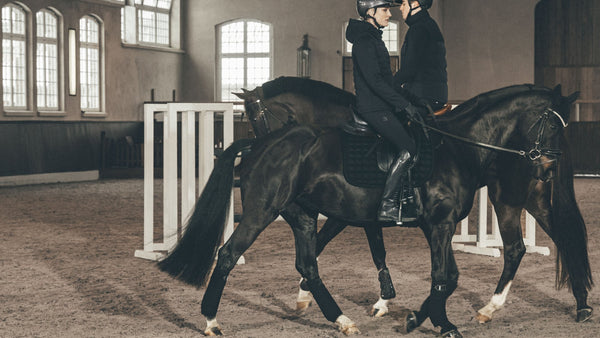 Deux cavaliers en tenue Pikeur Automne/Hiver 2026 montant à cheval dans un manège